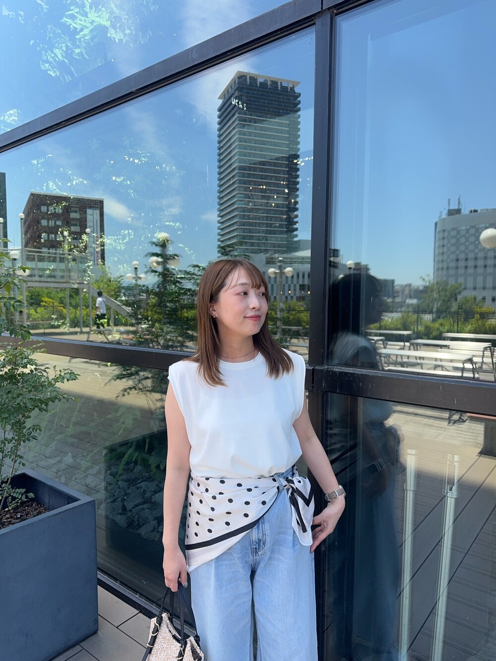 ホワイト系のタンクトップ、ブルー系のデニムパンツ、ブラック系のショルダーバッグを着用したレディースの夏コーディネートの3枚目の写真