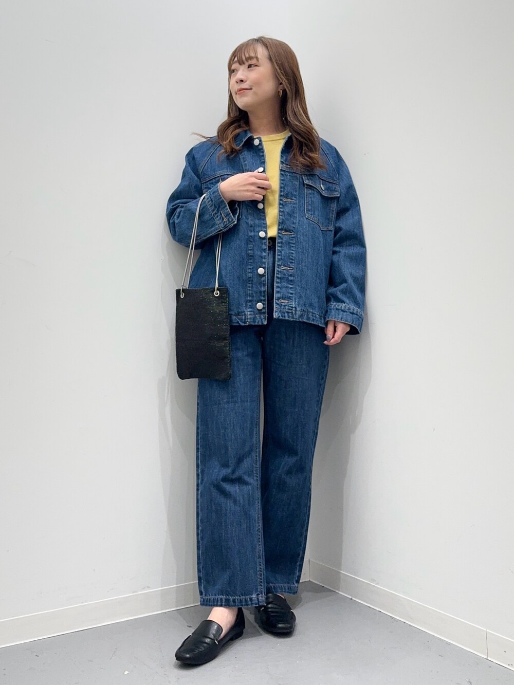 ブルー系のカバーオール、ブルー系のデニムパンツ、イエロー系のニット/セーターを着用したレディースの春コーディネートの3枚目の写真