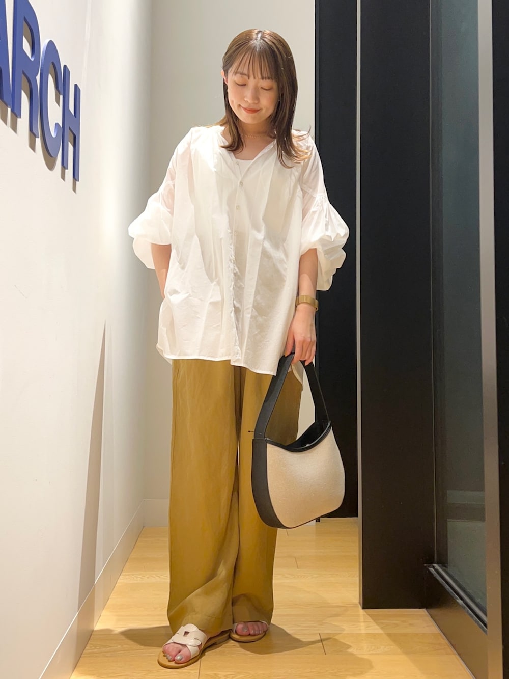 ホワイト系のシャツ/ブラウス、イエロー系のその他パンツ、ブラック系のハンドバッグを着用したレディースの夏コーディネートの2枚目の写真