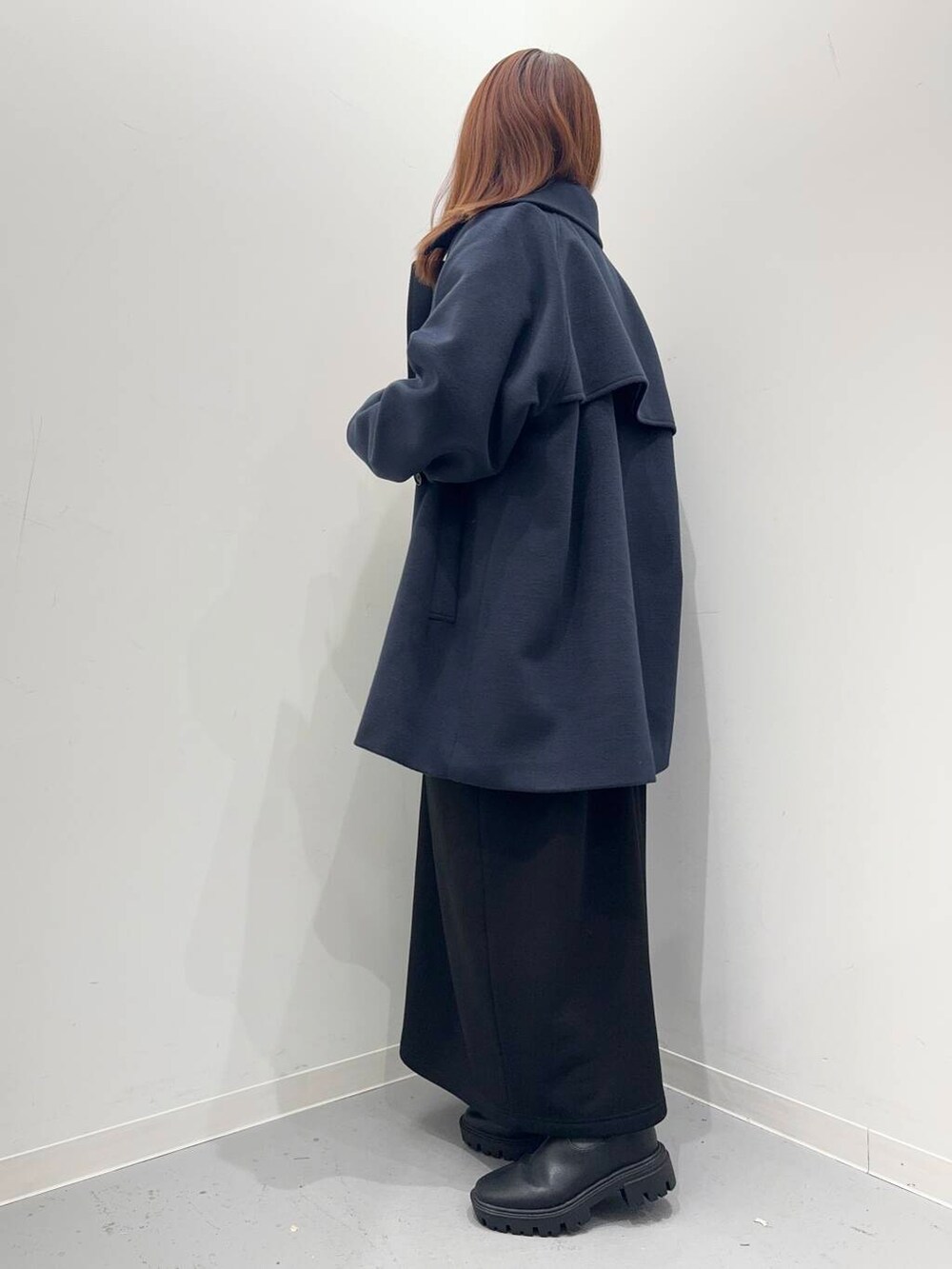 ブラック系のショルダーバッグ、ブラック系のブーツ、ブルー系のステンカラーコートを着用したレディースの冬コーディネートの3枚目の写真