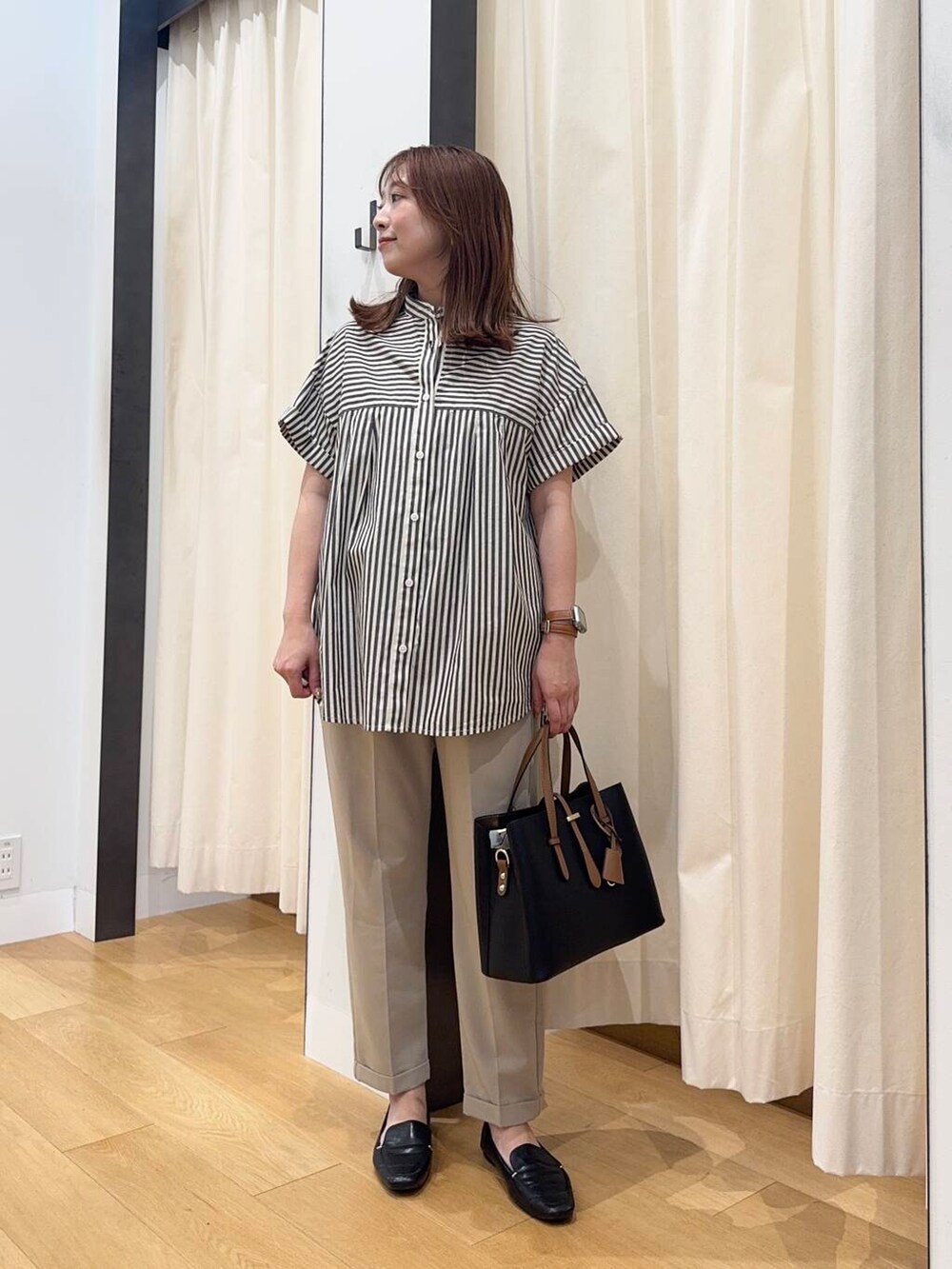 ブラック系のローファー、ブラック系のトートバッグ、ベージュ系のその他パンツを着用したレディースの夏コーディネートの2枚目の写真