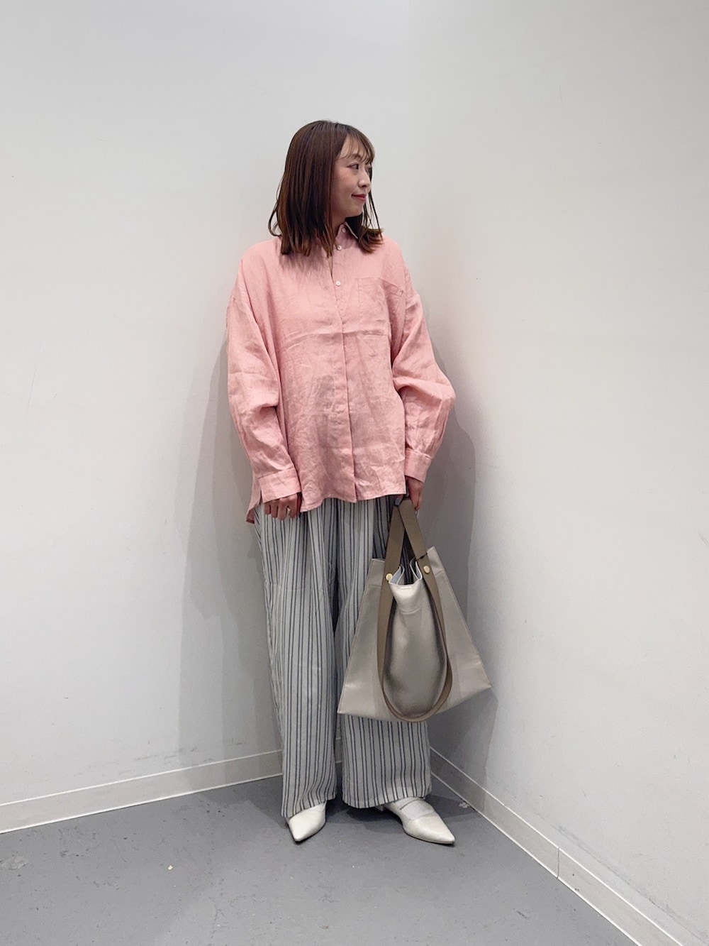 ピンク系のシャツ/ブラウス、グレー系のその他パンツ、ホワイト系のトートバッグを着用したレディースの春コーディネートの4枚目の写真