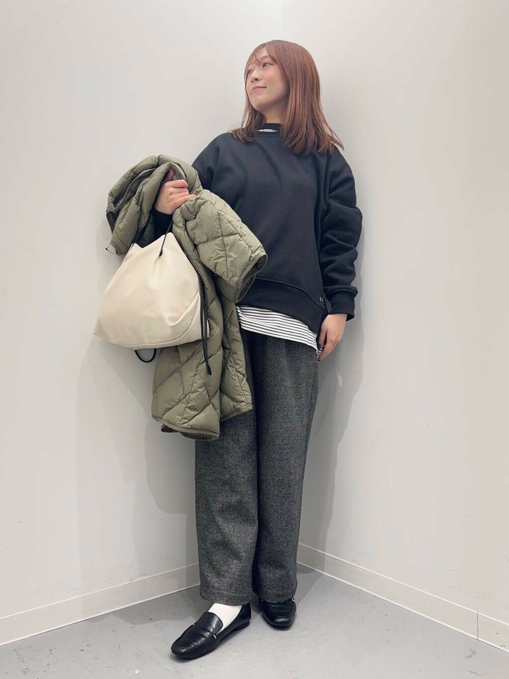 ブラック系のローファー、ホワイト系のショルダーバッグ、グリーン系のダウンジャケット/コートを着用したレディースの秋コーディネートの5枚目の写真