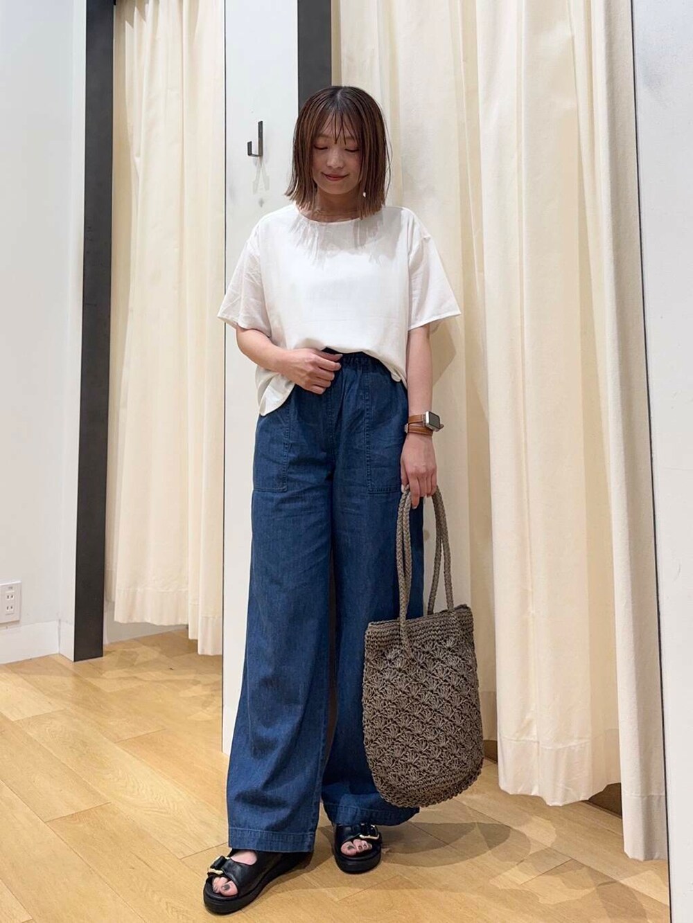 グレー系のトートバッグ、ブルー系のデニムパンツ、ブラック系のサンダルを着用したレディースの夏コーディネートの2枚目の写真