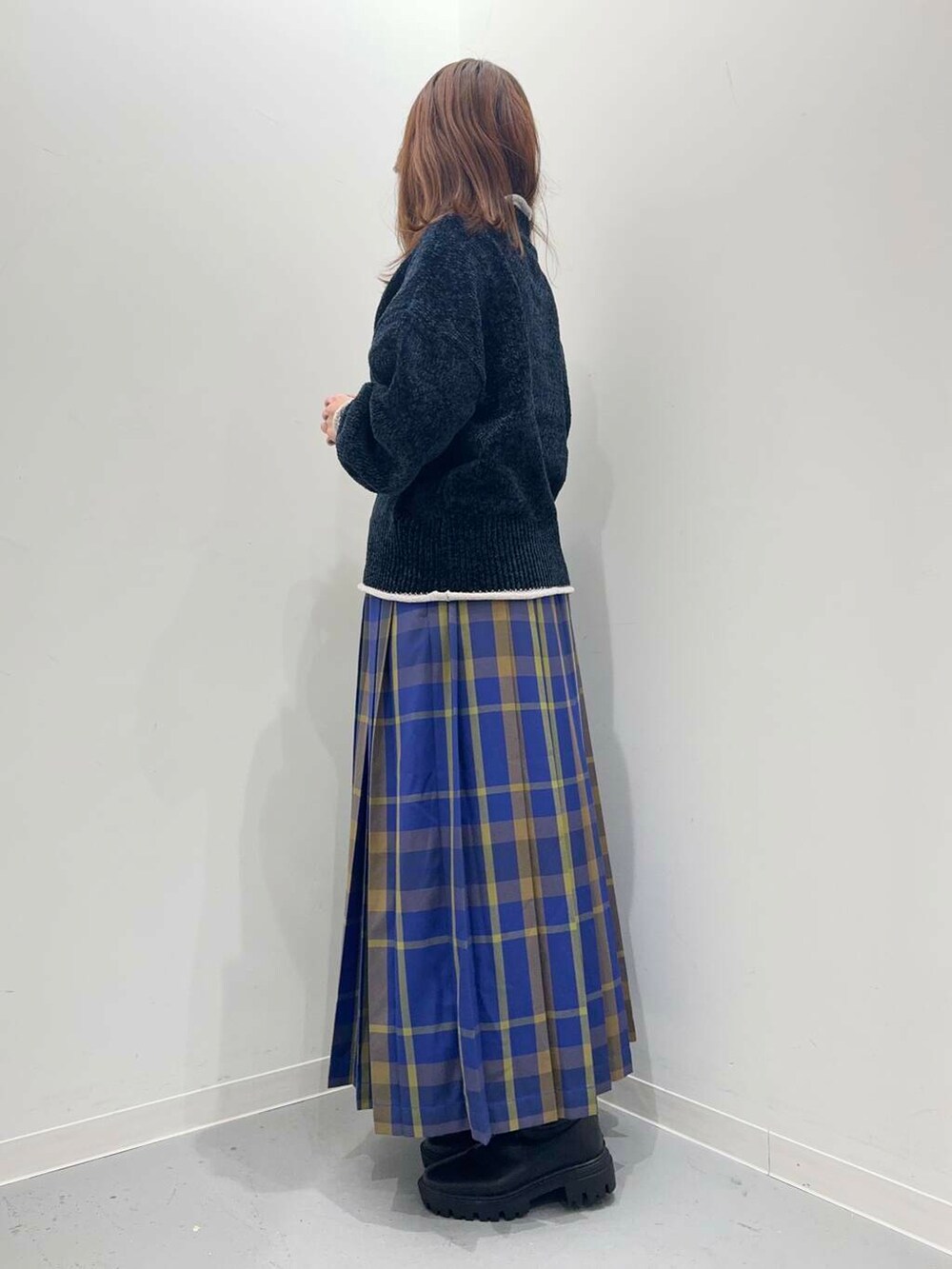 ブラック系のハンドバッグ、ブラック系のブーツ、ブルー系のスカートを着用したレディースの秋コーディネートの2枚目の写真