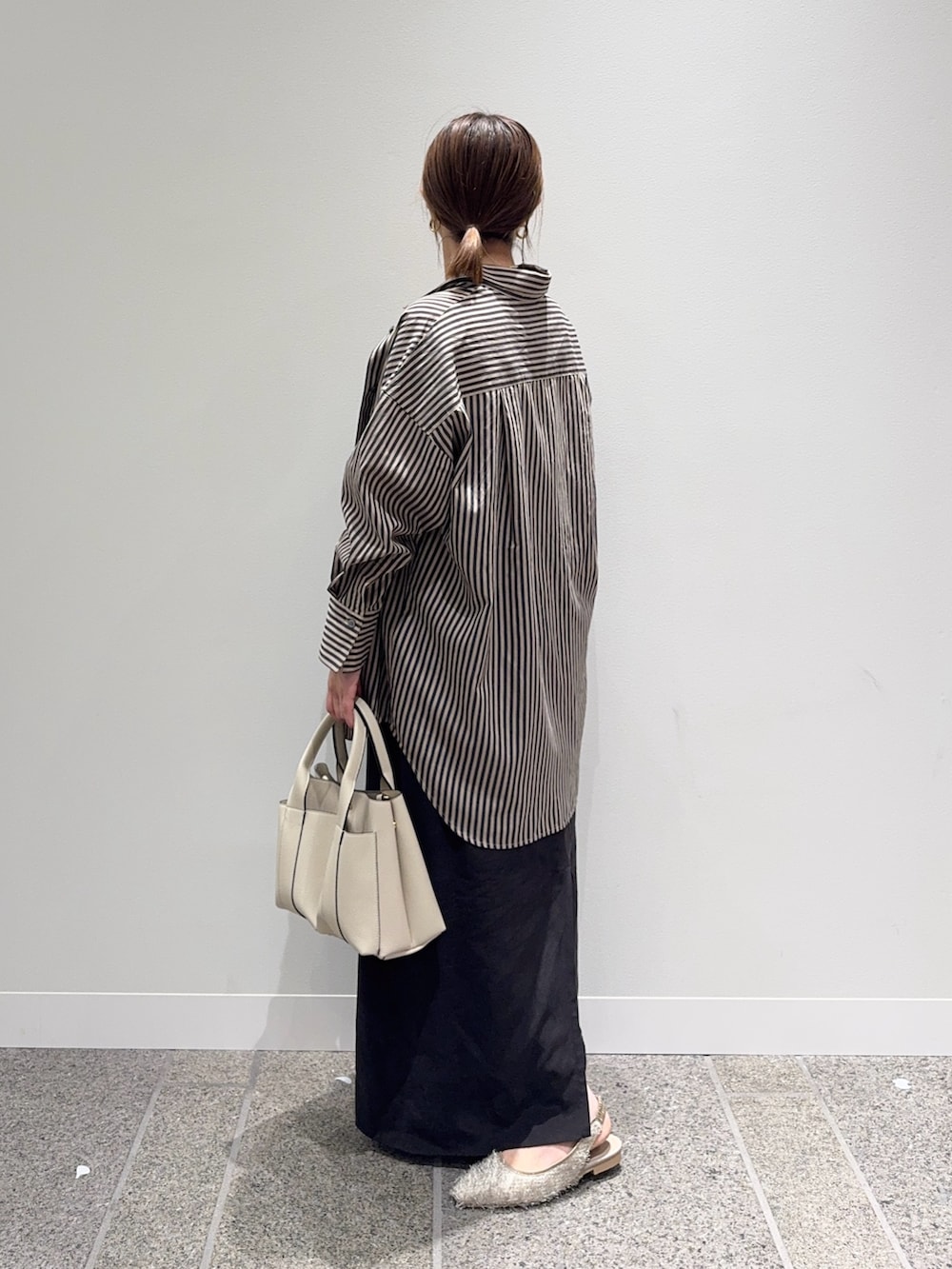 グレー系のシャツ/ブラウス、ブラウン系のスカート、ホワイト系のトートバッグを着用したレディースの秋コーディネートの3枚目の写真