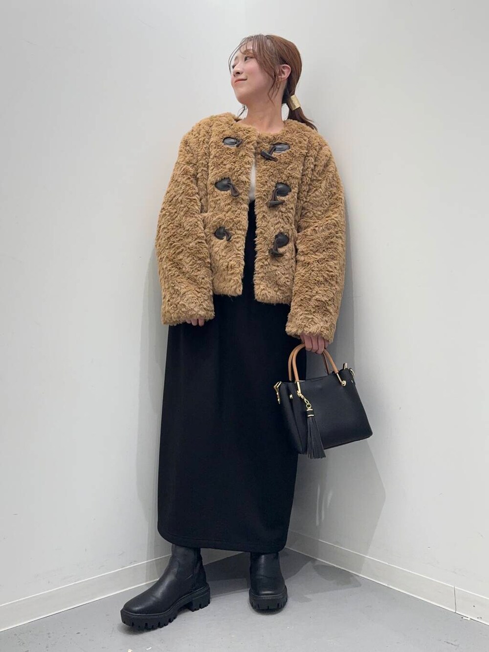 ブラック系のトートバッグ、ブラック系のブーツ、イエロー系のその他アウターを着用したレディースの冬コーディネートの5枚目の写真