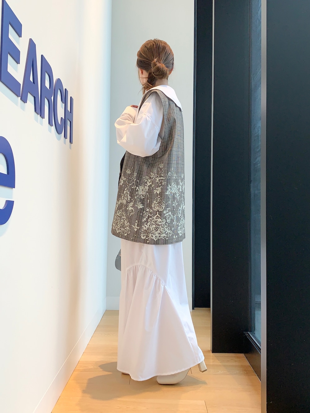 ブラウン系のベスト、ホワイト系のワンピースを着用したレディースの冬コーディネートの3枚目の写真