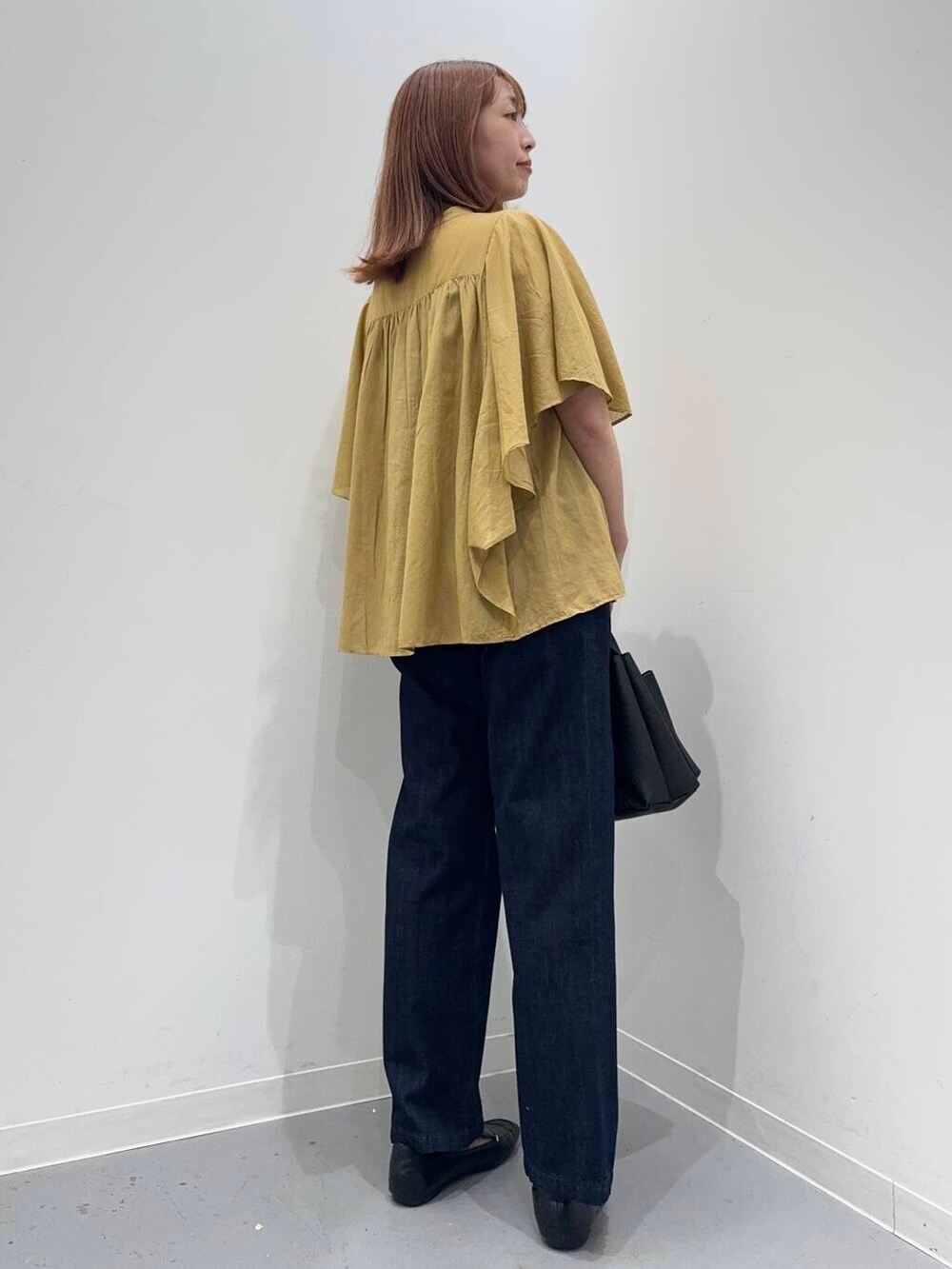 ブラック系のローファー、ブラック系のトートバッグ、ブルー系のデニムパンツを着用したレディースの夏コーディネートの4枚目の写真