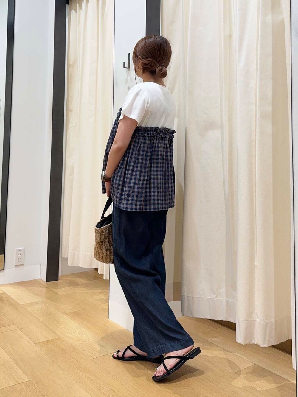 ベージュ系のハンドバッグ、ブルー系のデニムパンツ、ブラック系のサンダルを着用したレディースの夏コーディネートの3枚目の写真