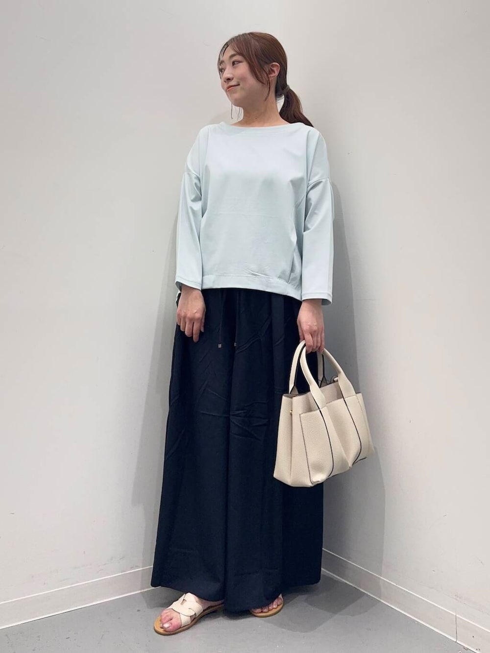 ホワイト系のトートバッグ、ブルー系のTシャツ/カットソー、ホワイト系のサンダルを着用したレディースの春コーディネートの5枚目の写真