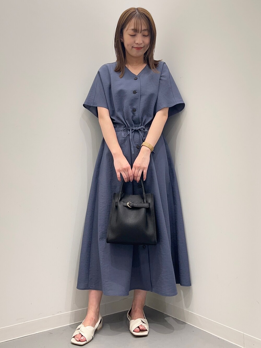 ブルー系のワンピース、ホワイト系のパンプス、ブラック系のトートバッグを着用したレディースの春コーディネートの2枚目の写真