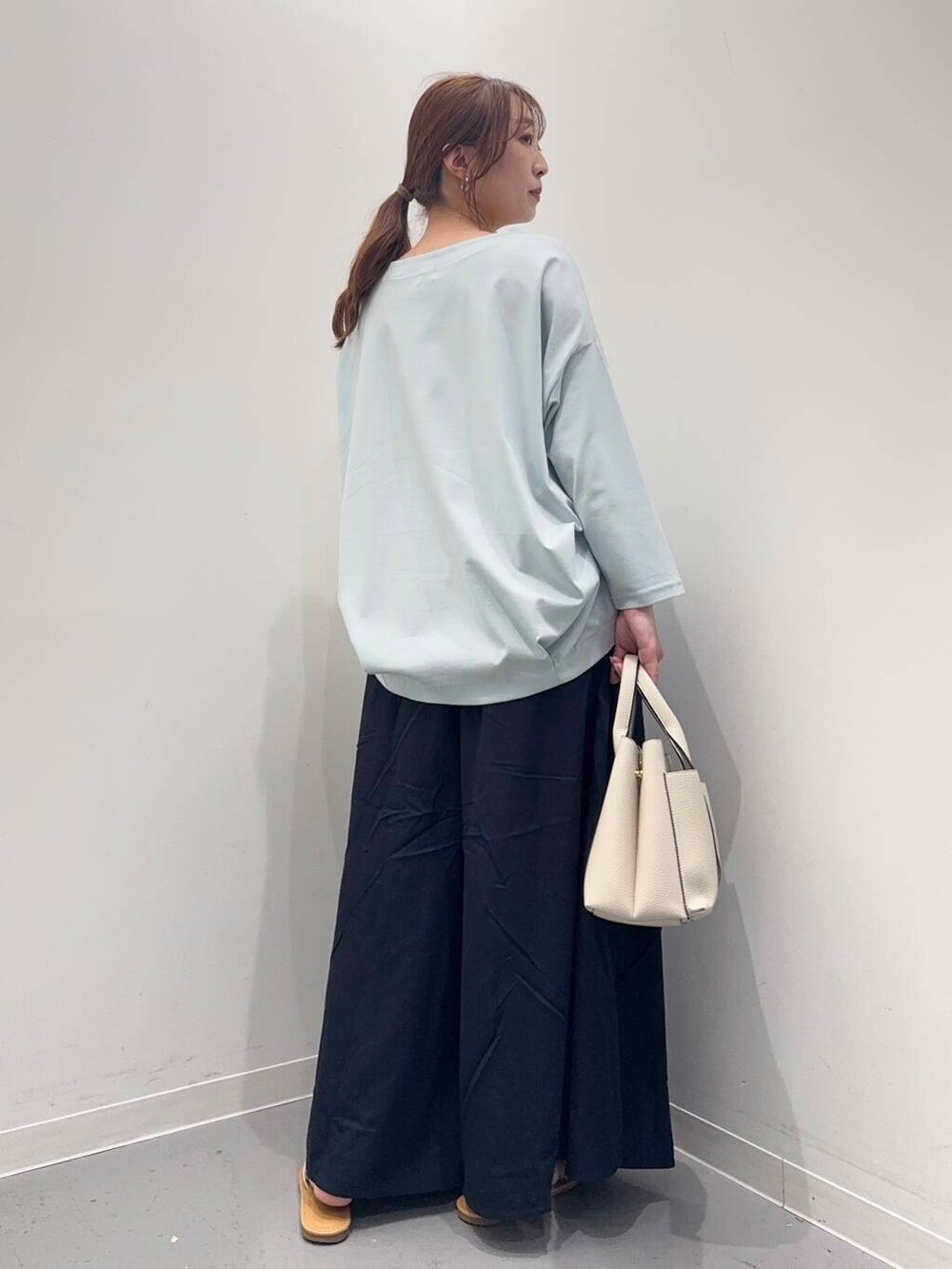 ホワイト系のトートバッグ、ブルー系のTシャツ/カットソー、ホワイト系のサンダルを着用したレディースの春コーディネートの4枚目の写真