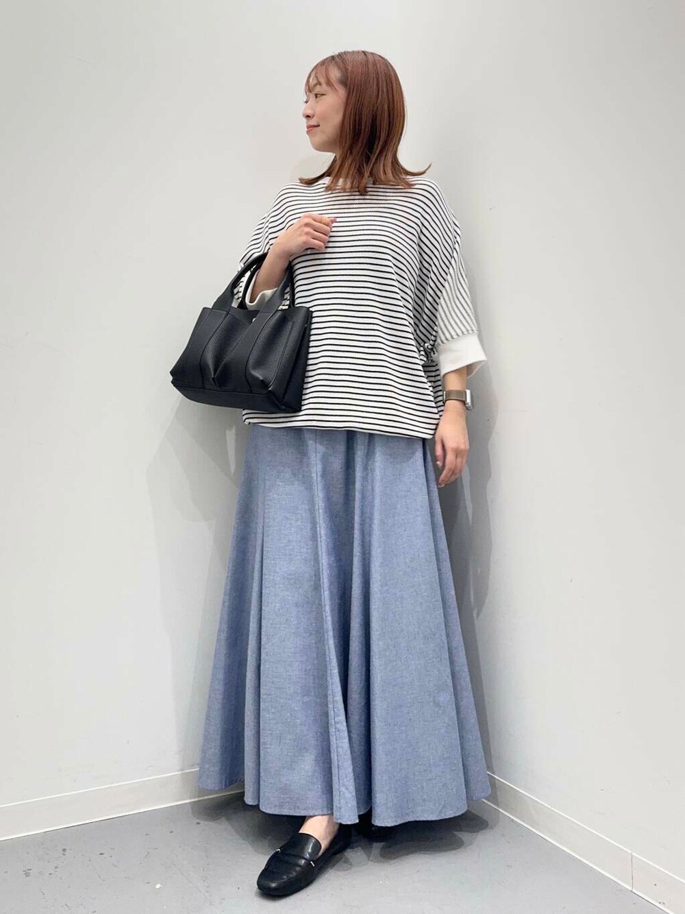 ブラック系のローファー、ブラック系のトートバッグ、ホワイト系のTシャツ/カットソーを着用したレディースの夏コーディネートの2枚目の写真