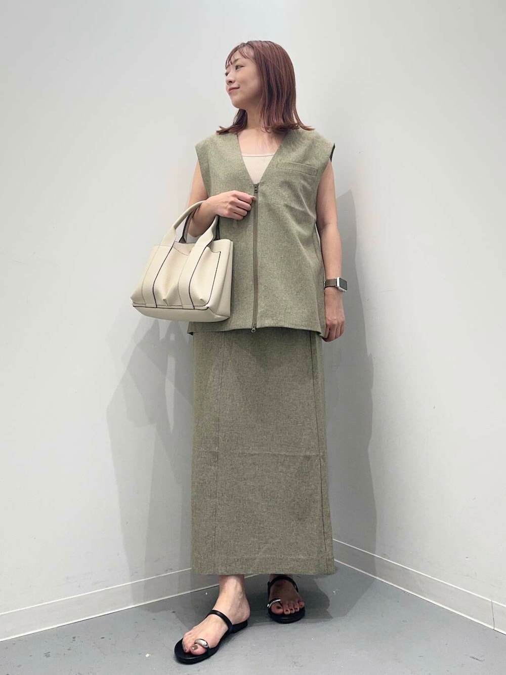 ホワイト系のトートバッグ、ブラック系のサンダル、グリーン系のベストを着用したレディースの夏コーディネートの4枚目の写真