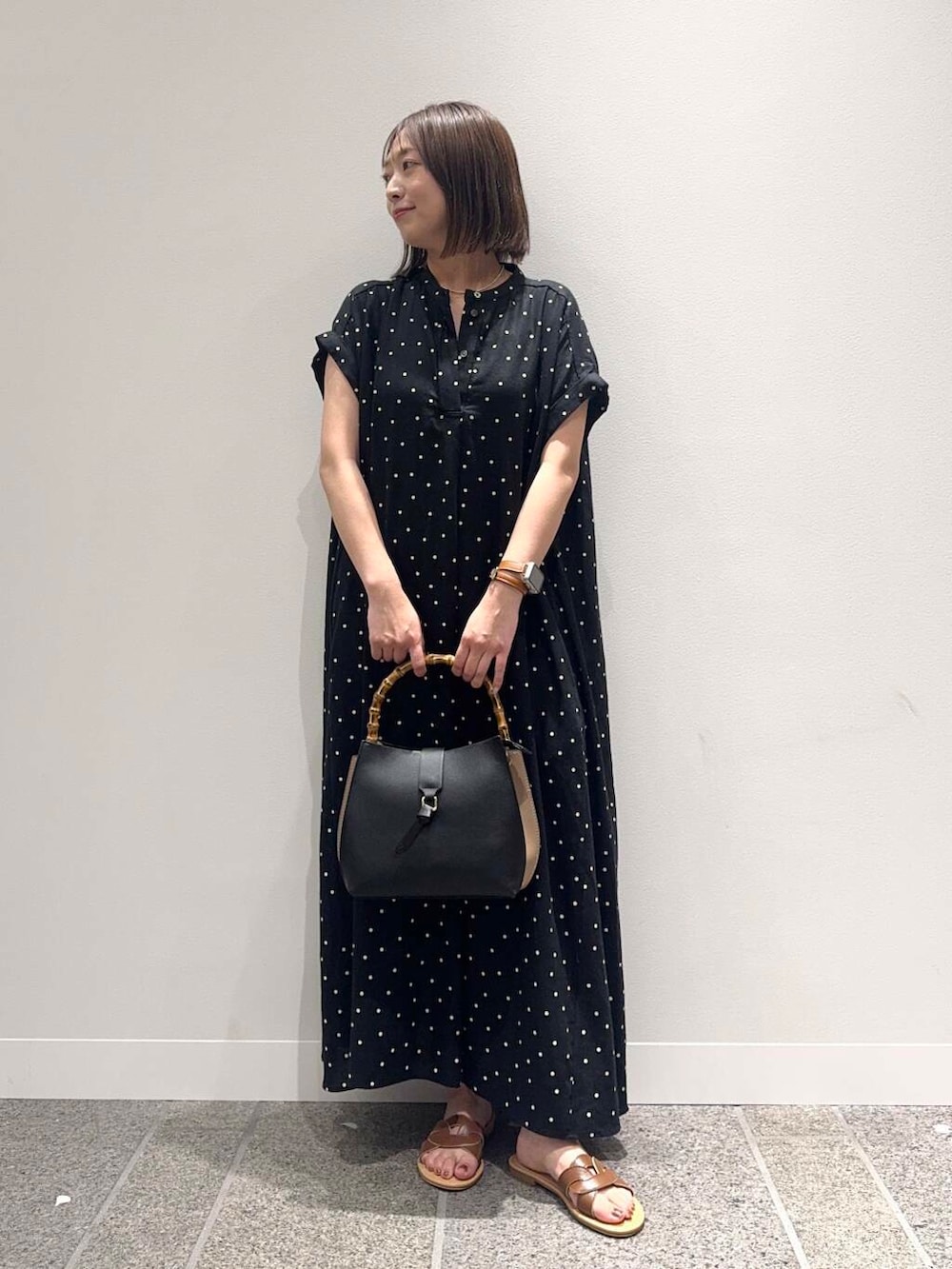 ブラウン系のサンダル、ブラック系のハンドバッグ、ブラック系のワンピースを着用したレディースの夏コーディネートの6枚目の写真