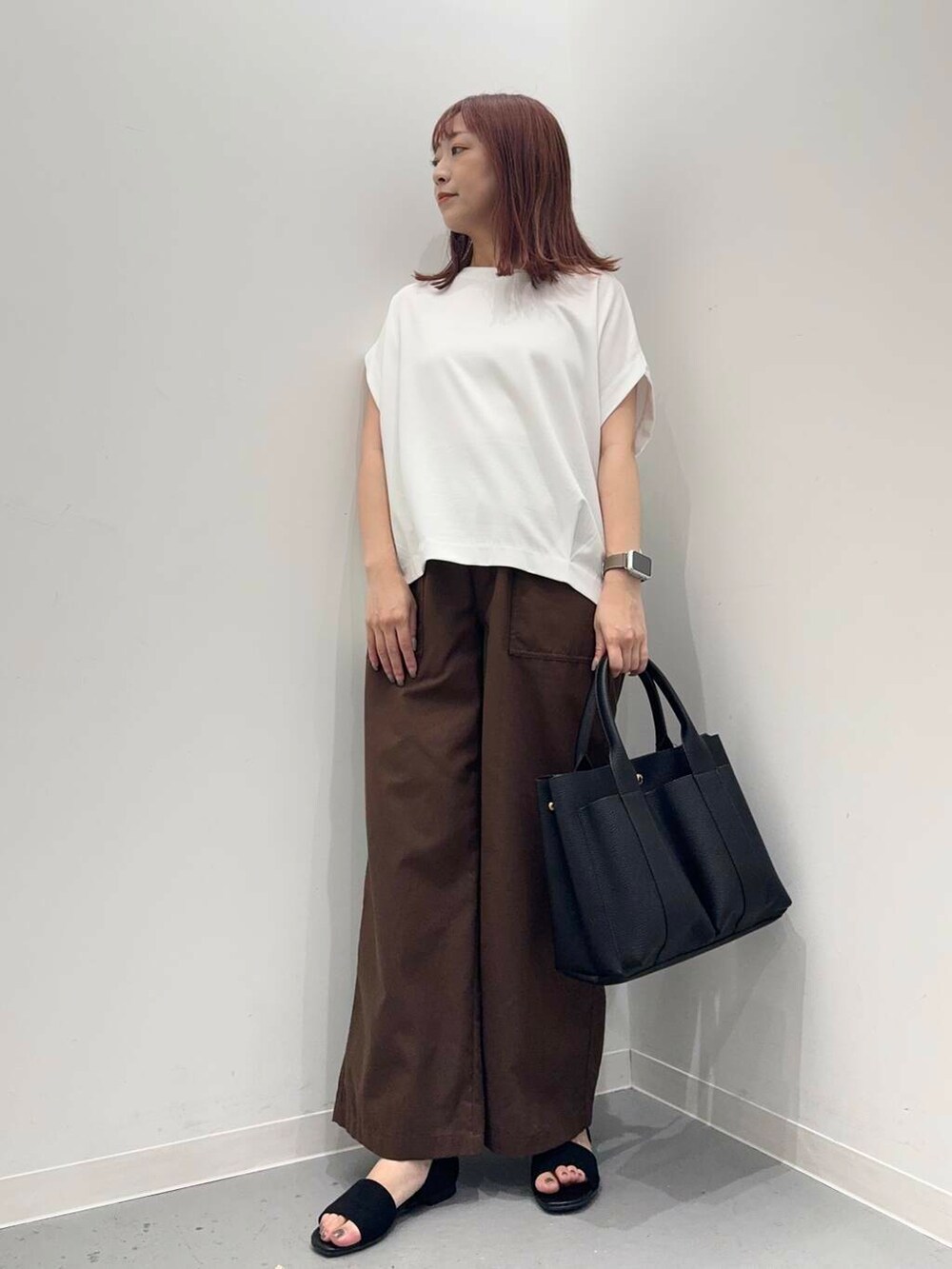 ブラック系のトートバッグ、ホワイト系のTシャツ/カットソー、ブラック系のサンダルを着用したレディースの夏コーディネートの4枚目の写真