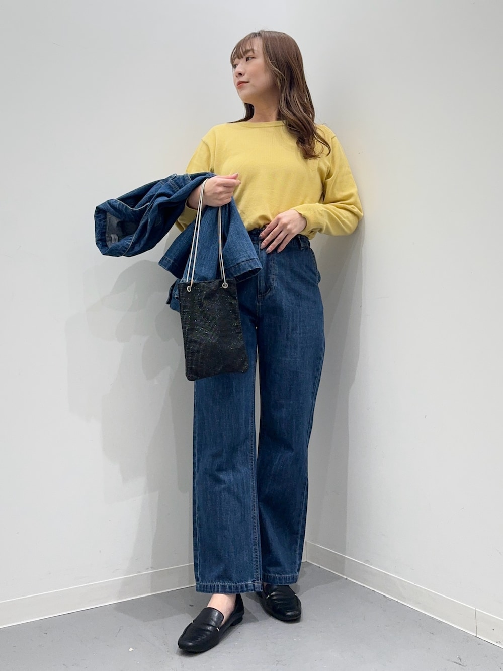 ブルー系のカバーオール、ブルー系のデニムパンツ、イエロー系のニット/セーターを着用したレディースの春コーディネートの6枚目の写真