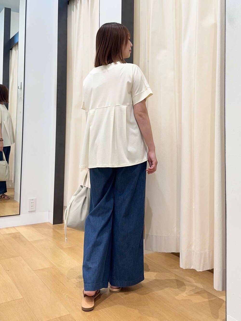 ブラウン系のサンダル、ブルー系のデニムパンツ、ホワイト系のショルダーバッグを着用したレディースの夏コーディネートの4枚目の写真