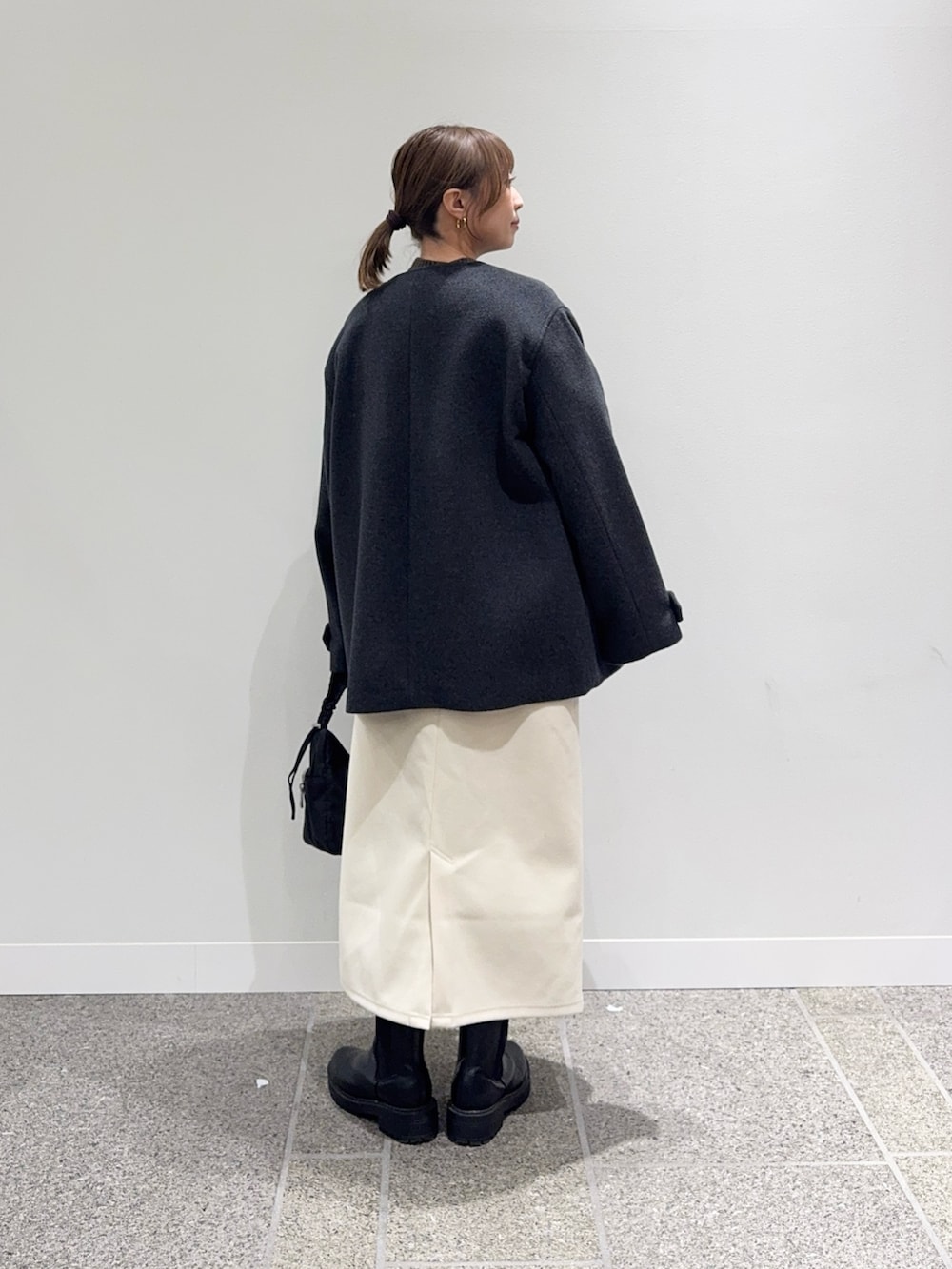 グレー系のピーコート、ブラウン系のニット/セーター、ホワイト系のスカートを着用したレディースの冬コーディネートの4枚目の写真