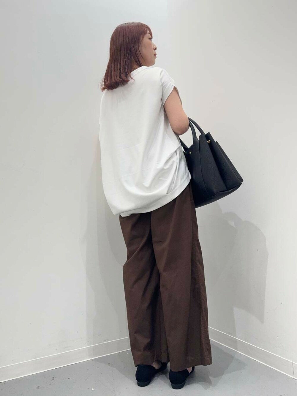ブラック系のトートバッグ、ホワイト系のTシャツ/カットソー、ブラック系のサンダルを着用したレディースの夏コーディネートの3枚目の写真