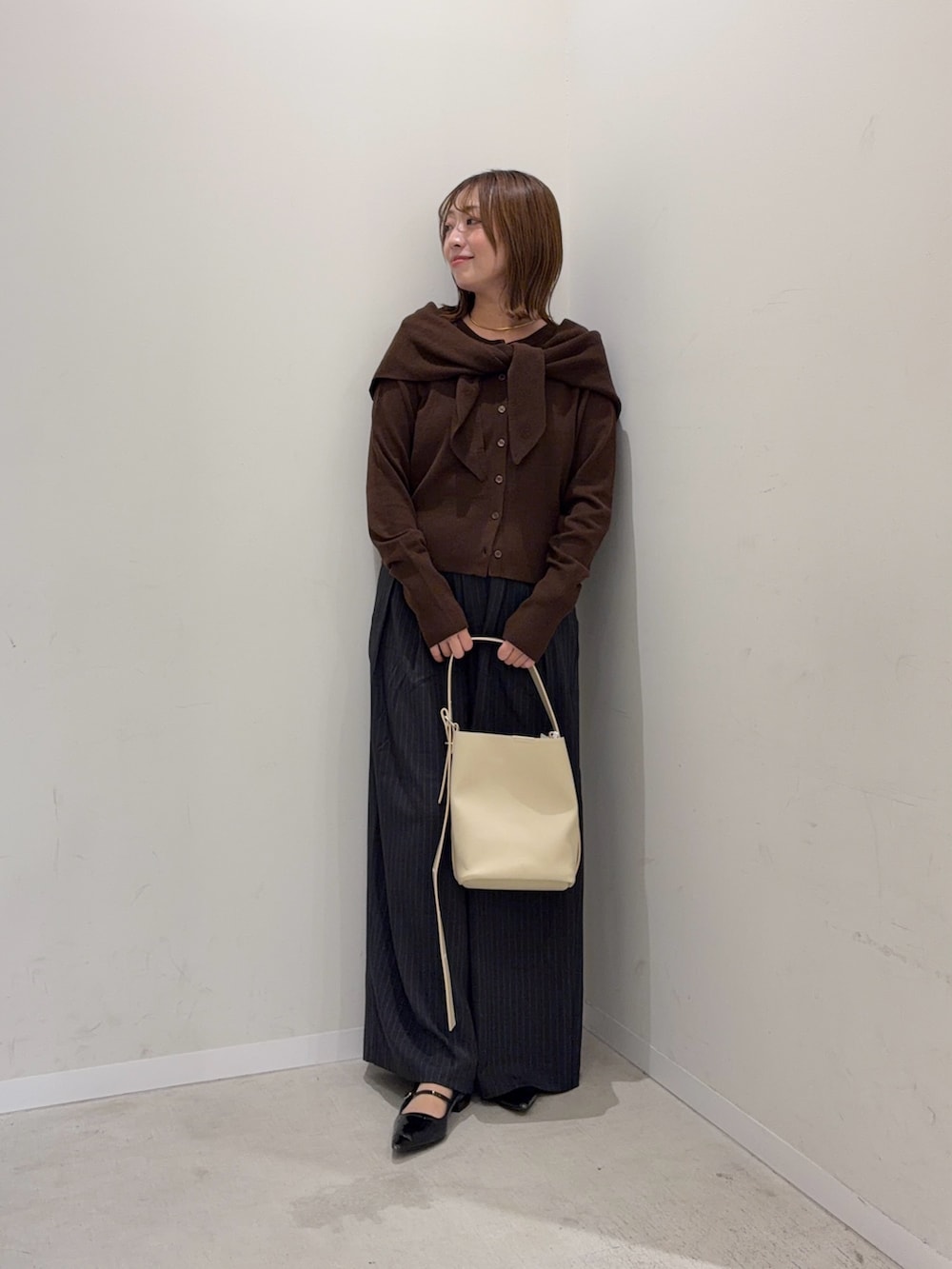 ブラウン系のカーディガン/ボレロ、グレー系のその他パンツ、ベージュ系のショルダーバッグを着用したレディースの秋コーディネートの4枚目の写真