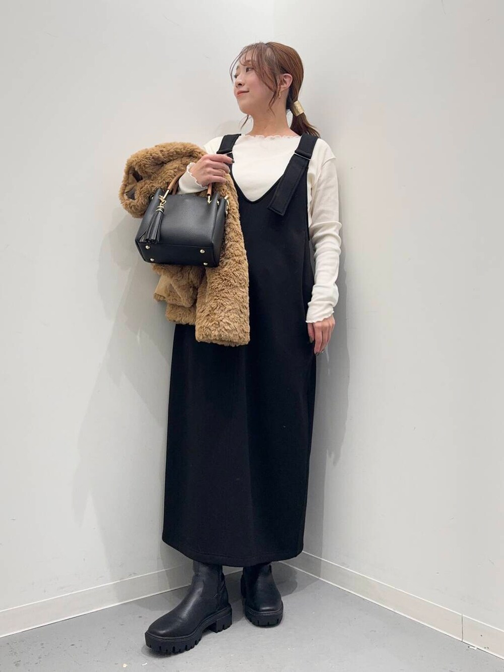 ブラック系のトートバッグ、ブラック系のブーツ、イエロー系のその他アウターを着用したレディースの冬コーディネートの6枚目の写真