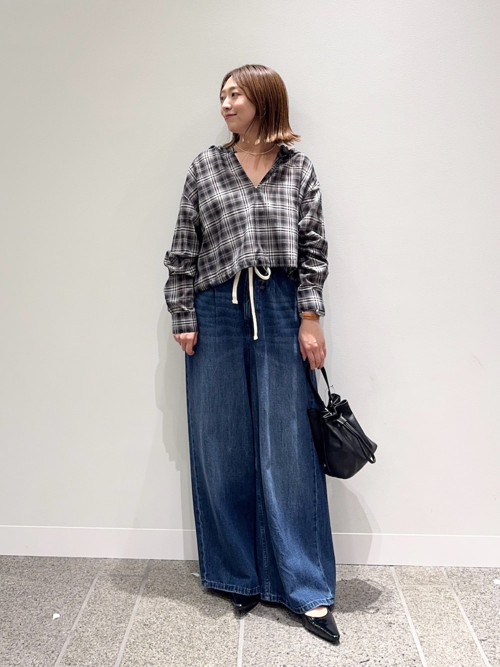 ブラック系のシャツ/ブラウス、ブルー系のデニムパンツ、ブラック系のパンプスを着用したレディースの秋コーディネートの5枚目の写真