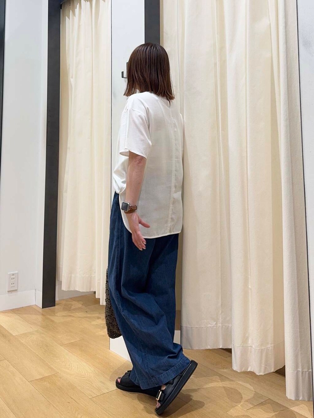 グレー系のトートバッグ、ブルー系のデニムパンツ、ブラック系のサンダルを着用したレディースの夏コーディネートの3枚目の写真