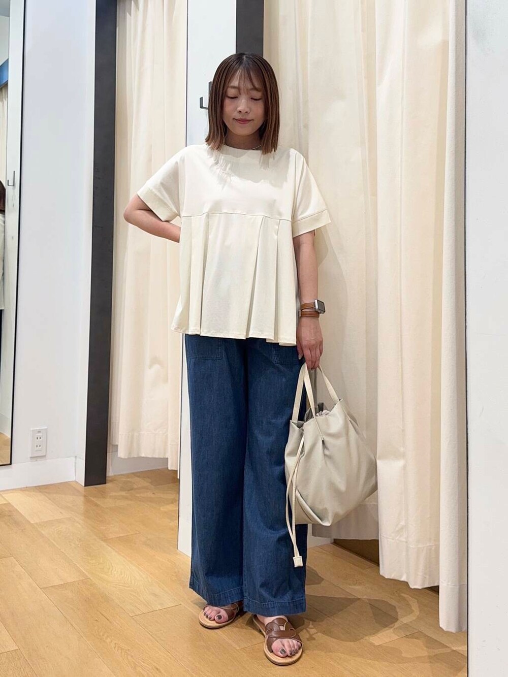 ブラウン系のサンダル、ブルー系のデニムパンツ、ホワイト系のショルダーバッグを着用したレディースの夏コーディネートの5枚目の写真