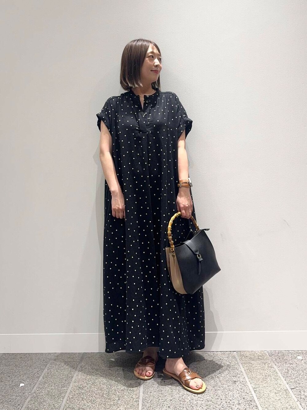 ブラウン系のサンダル、ブラック系のハンドバッグ、ブラック系のワンピースを着用したレディースの夏コーディネートの5枚目の写真