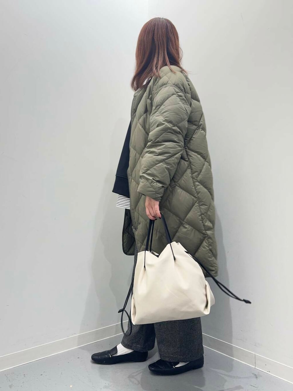 ブラック系のローファー、ホワイト系のショルダーバッグ、グリーン系のダウンジャケット/コートを着用したレディースの秋コーディネートの3枚目の写真