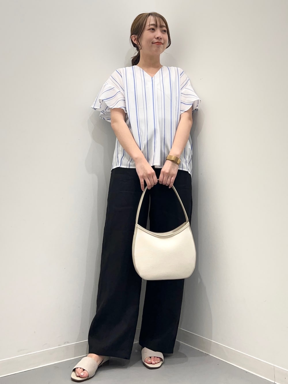 ブルー系のシャツ/ブラウス、ブラック系のその他パンツ、ベージュ系のハンドバッグを着用したレディースの春コーディネートの4枚目の写真