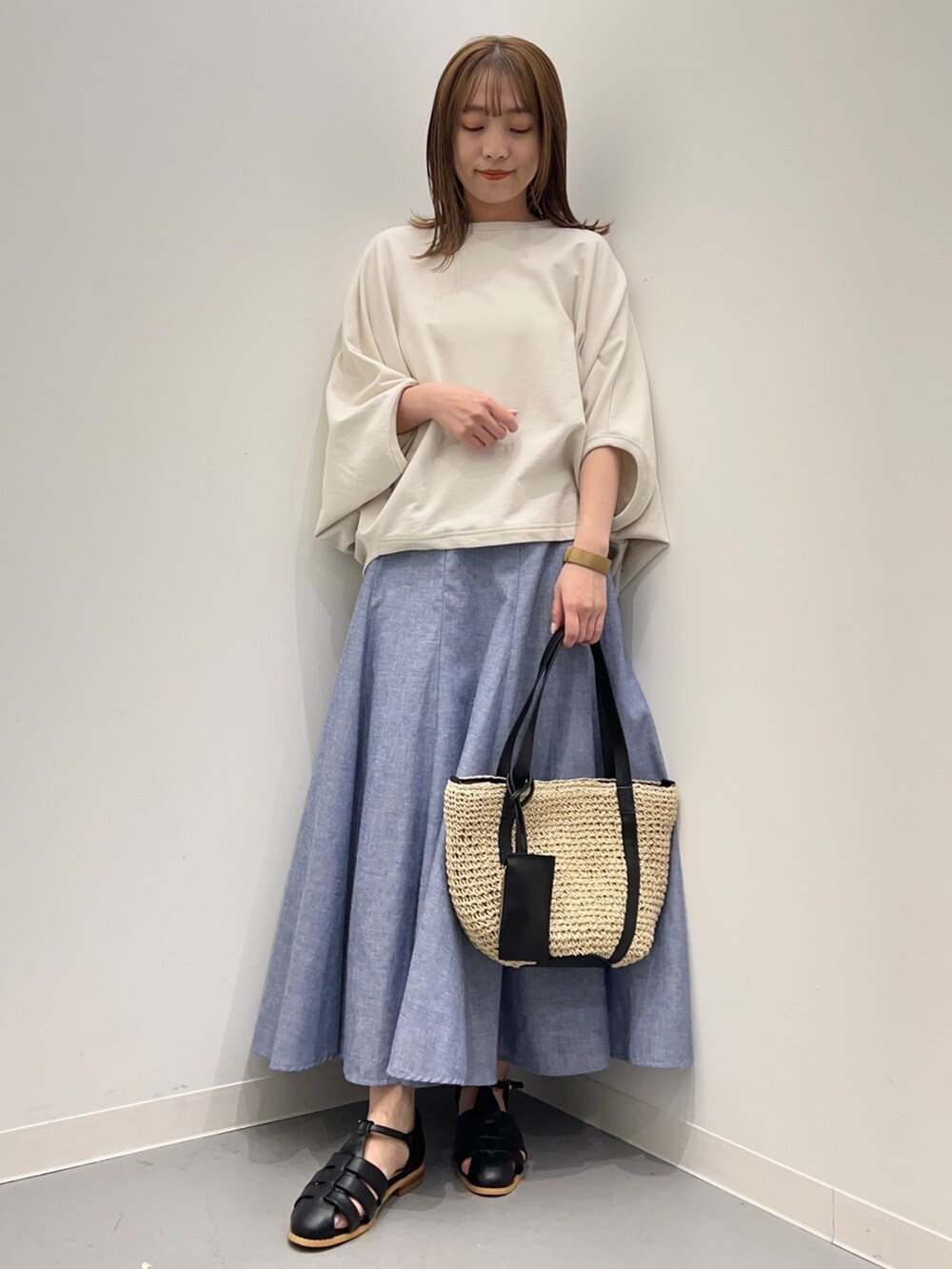 ベージュ系のTシャツ/カットソー、ブルー系のスカート、ブラック系のサンダルを着用したレディースの春コーディネートの2枚目の写真