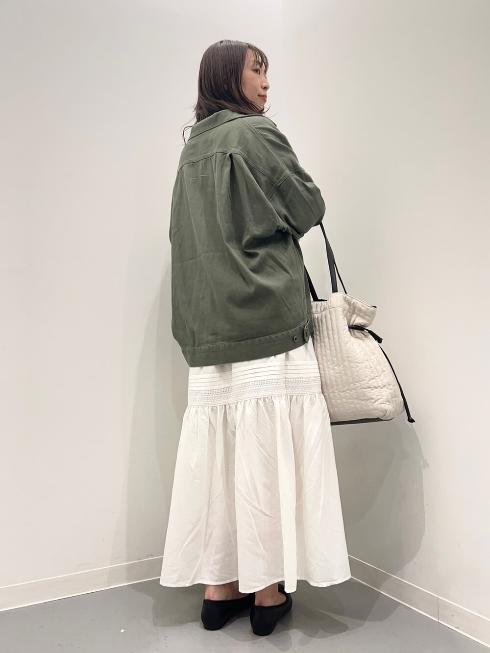 グリーン系のジャケット/アウター、ブラック系のニット/セーター、ホワイト系のスカートを着用したレディースの夏コーディネートの4枚目の写真