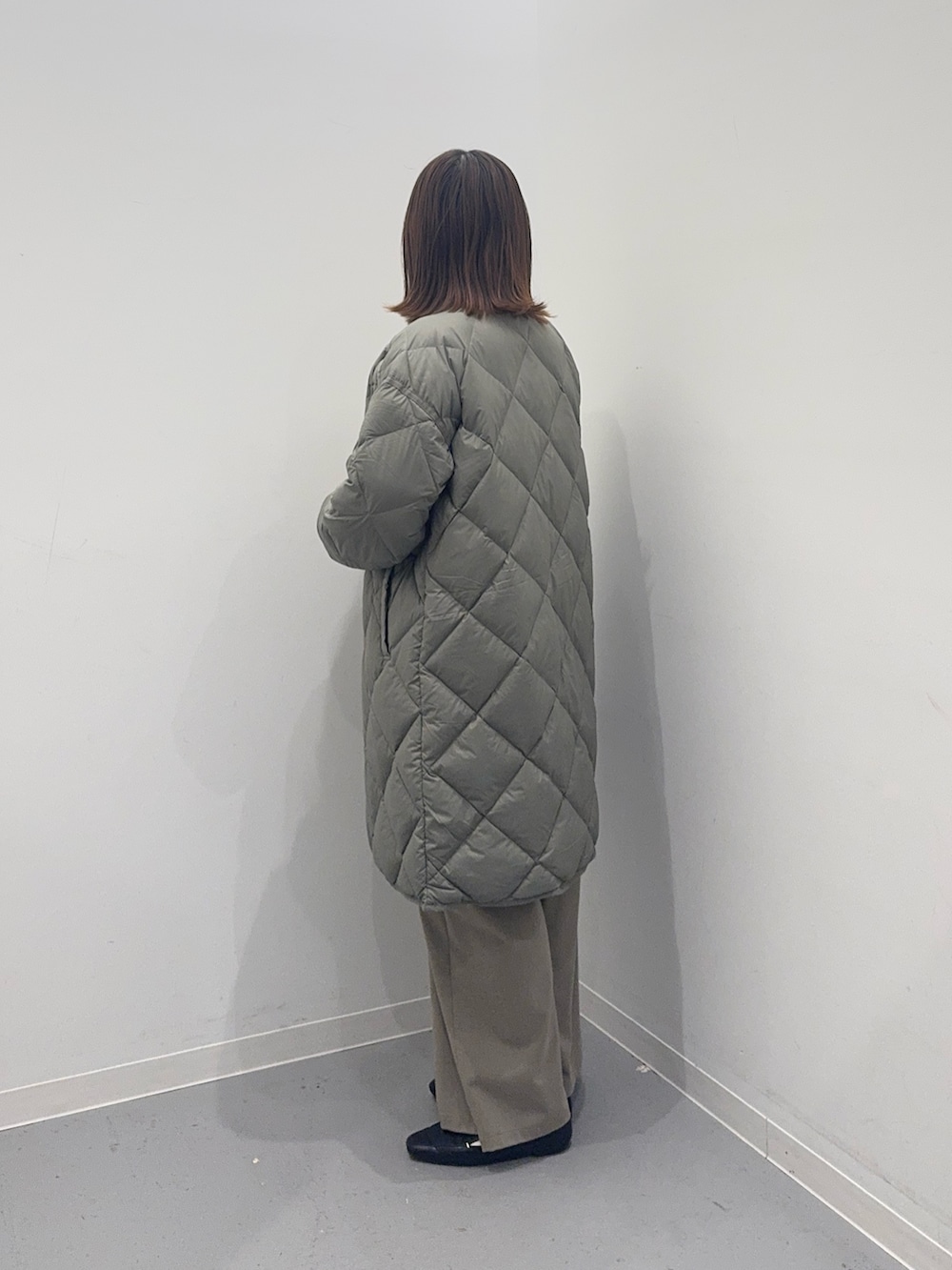 グリーン系のダウンジャケット/コート、ホワイト系のニット/セーター、ブラック系のボストンバッグを着用したレディースの冬コーディネートの2枚目の写真