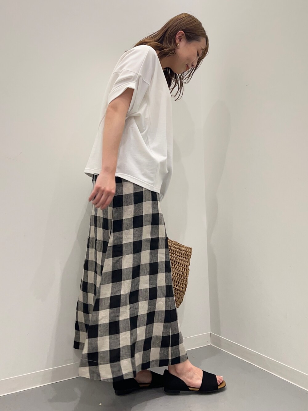 ホワイト系のTシャツ/カットソー、ブラック系のスカート、ベージュ系のかごバッグを着用したレディースの春コーディネートの6枚目の写真