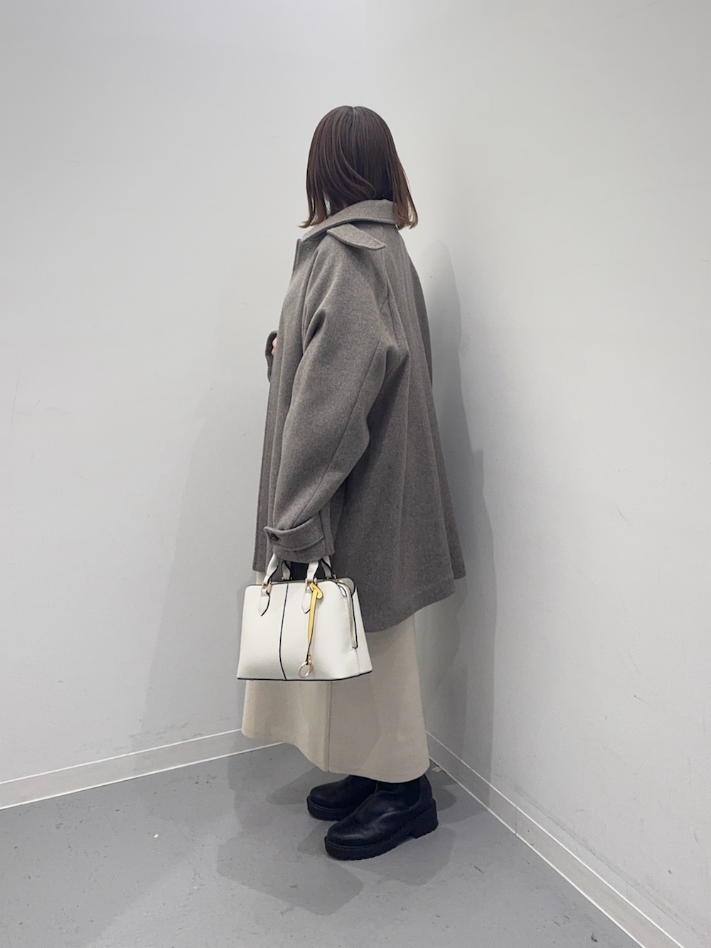 ベージュ系のその他アウター、ベージュ系のワンピース、ホワイト系のハンドバッグを着用したレディースの冬コーディネートの3枚目の写真