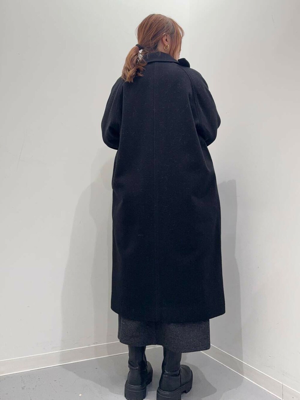 ブラック系のトートバッグ、ブラック系のブーツ、レッド系のニット/セーターを着用したレディースの冬コーディネートの3枚目の写真