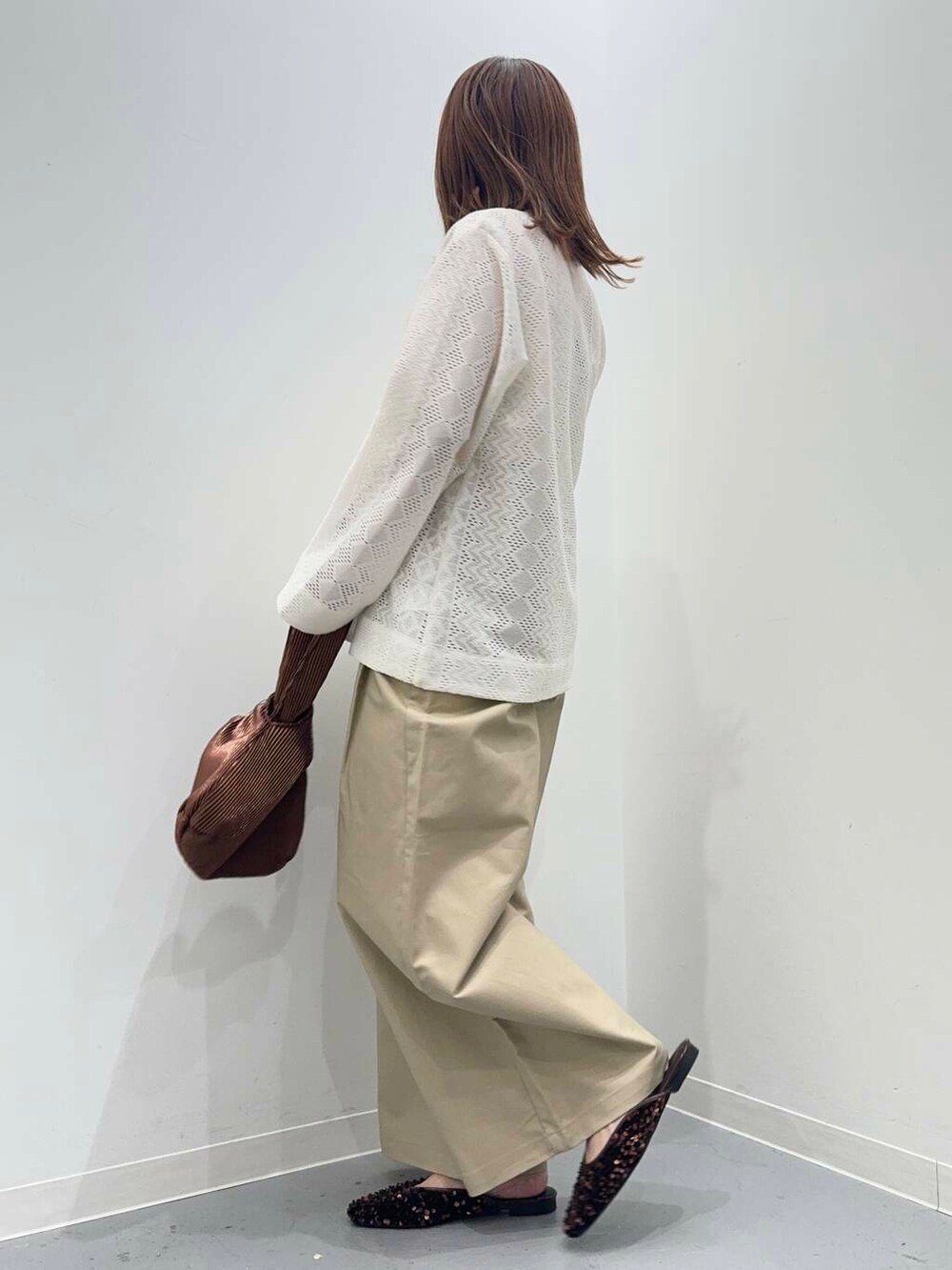 ブラウン系のハンドバッグ、ブラウン系のその他シューズ、ホワイト系のカーディガン/ボレロを着用したレディースの秋コーディネートの2枚目の写真