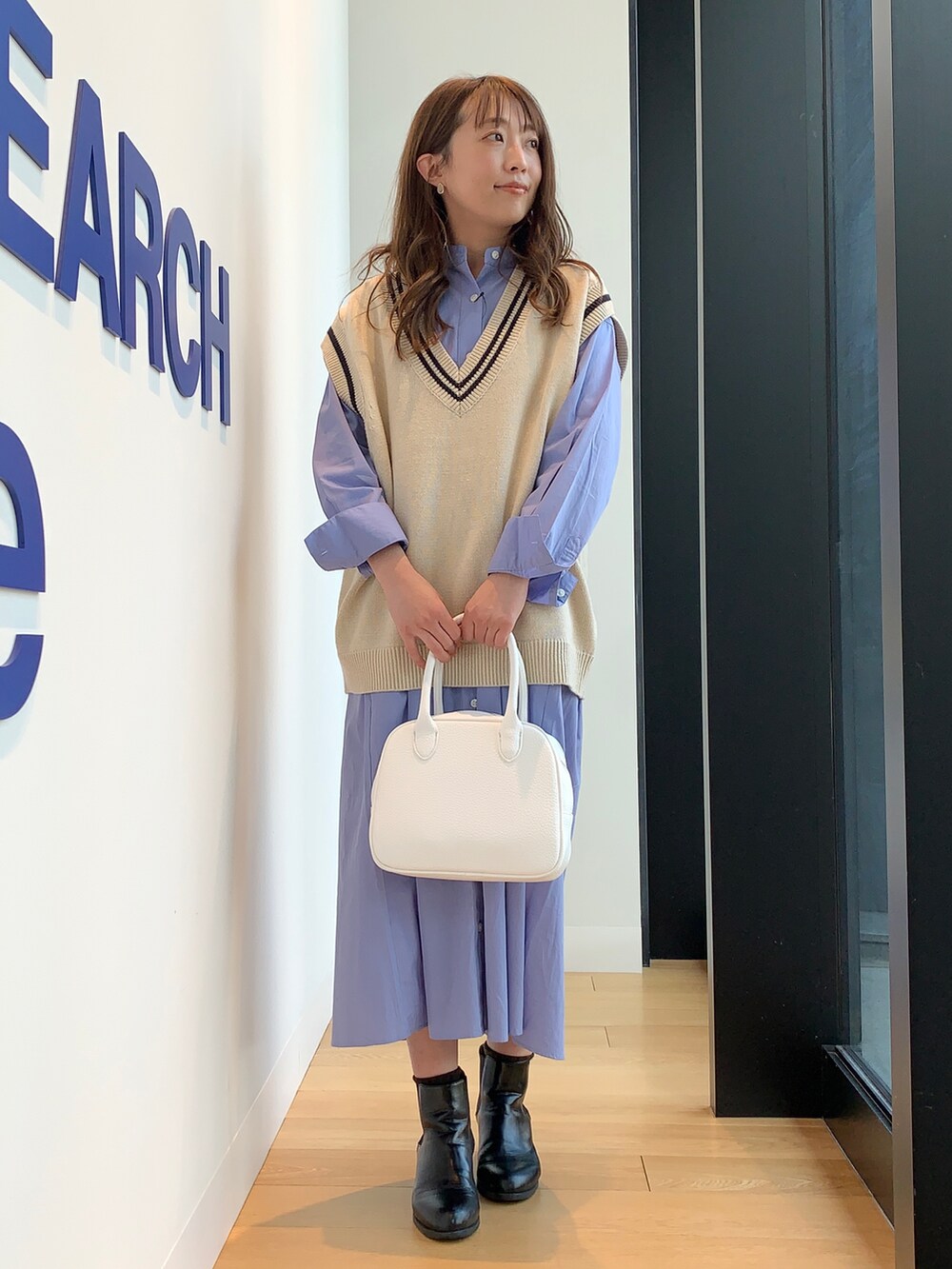 ベージュ系のニット/セーター、ブルー系のワンピース、ホワイト系のボストンバッグを着用したレディースの冬コーディネートの2枚目の写真