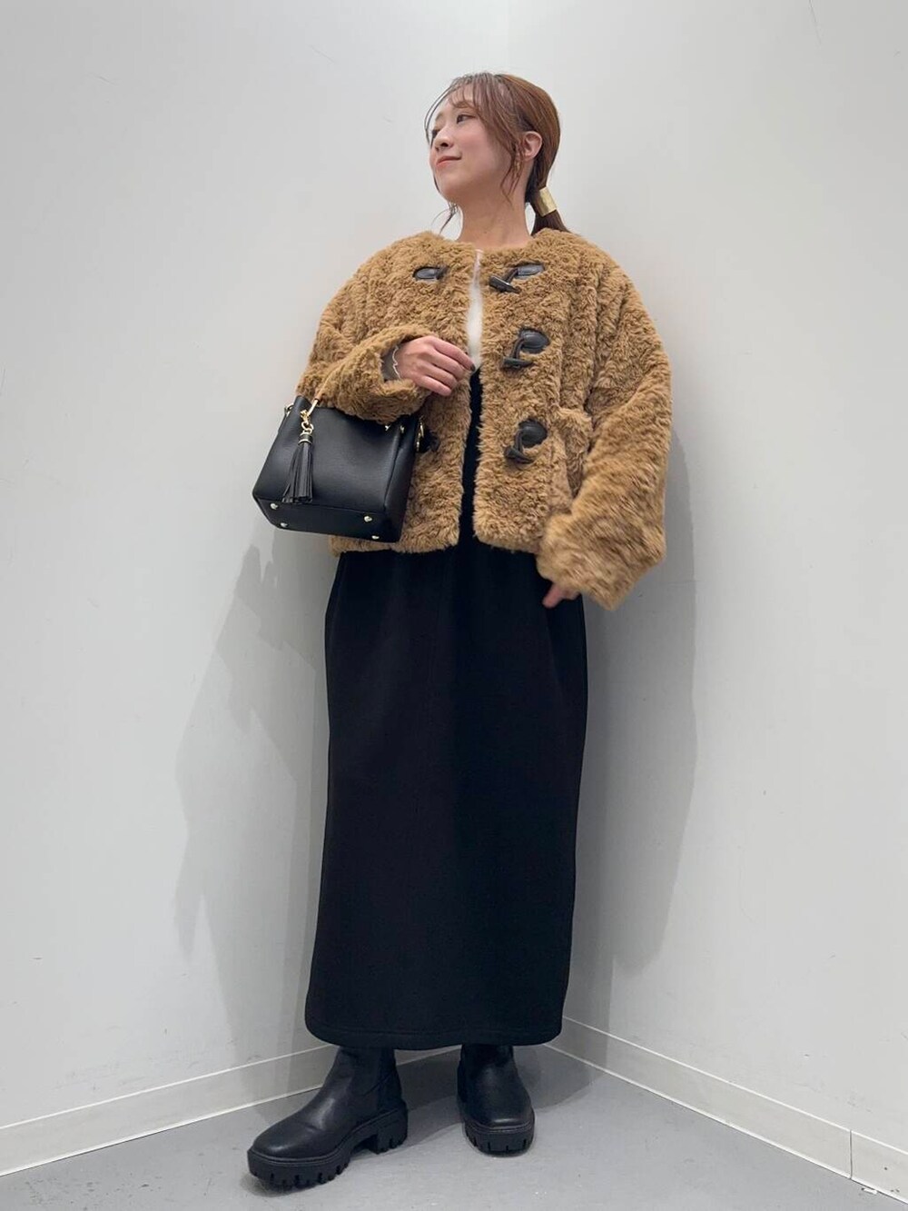 ブラック系のトートバッグ、ブラック系のブーツ、イエロー系のその他アウターを着用したレディースの冬コーディネートの2枚目の写真