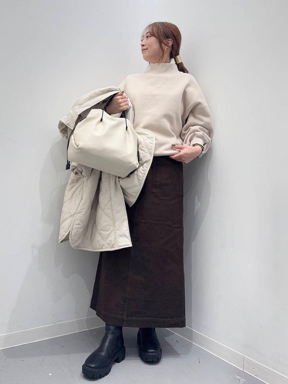 ホワイト系のショルダーバッグ、ブラック系のブーツ、ベージュ系のその他アウターを着用したレディースの冬コーディネートの2枚目の写真