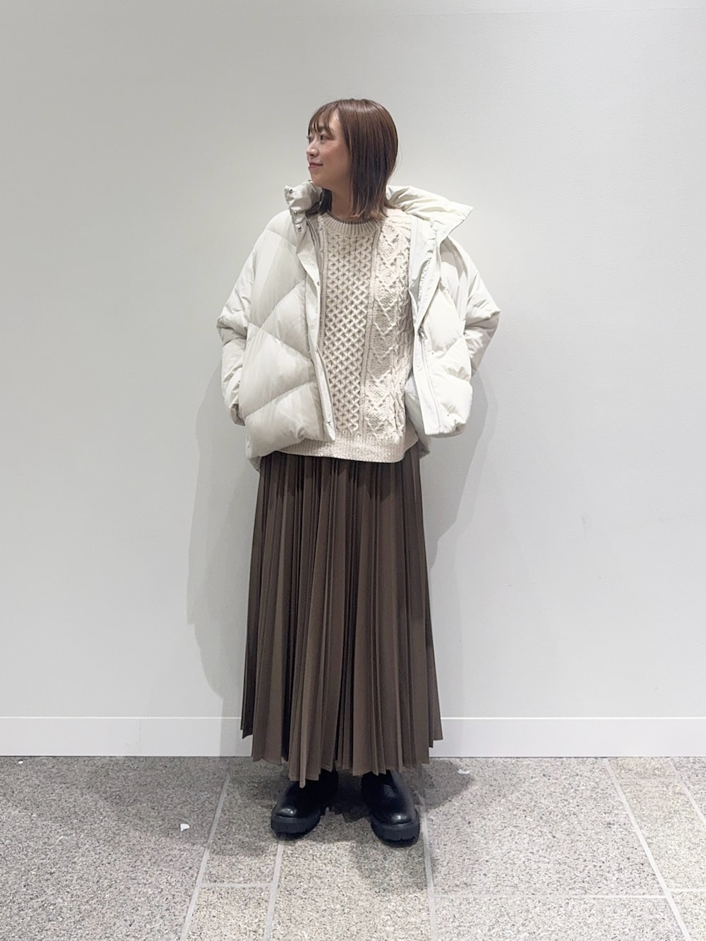 ホワイト系のダウンジャケット/コート、ホワイト系のニット/セーター、ベージュ系のスカートを着用したレディースの冬コーディネートの2枚目の写真