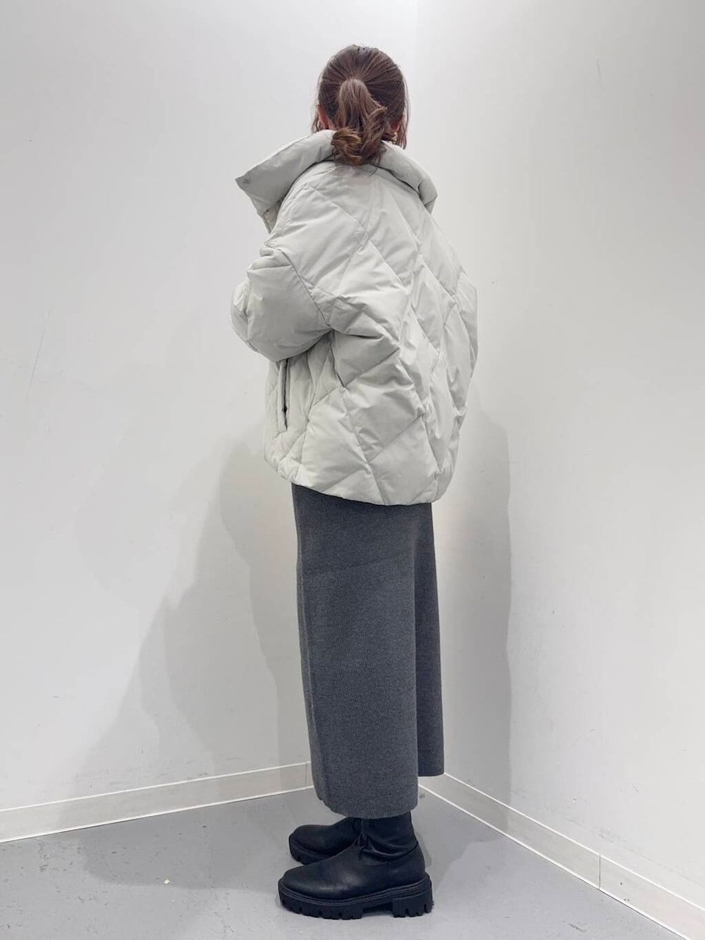 ホワイト系のトートバッグ、ブラック系のブーツ、グレー系のダウンジャケット/コートを着用したレディースの冬コーディネートの2枚目の写真