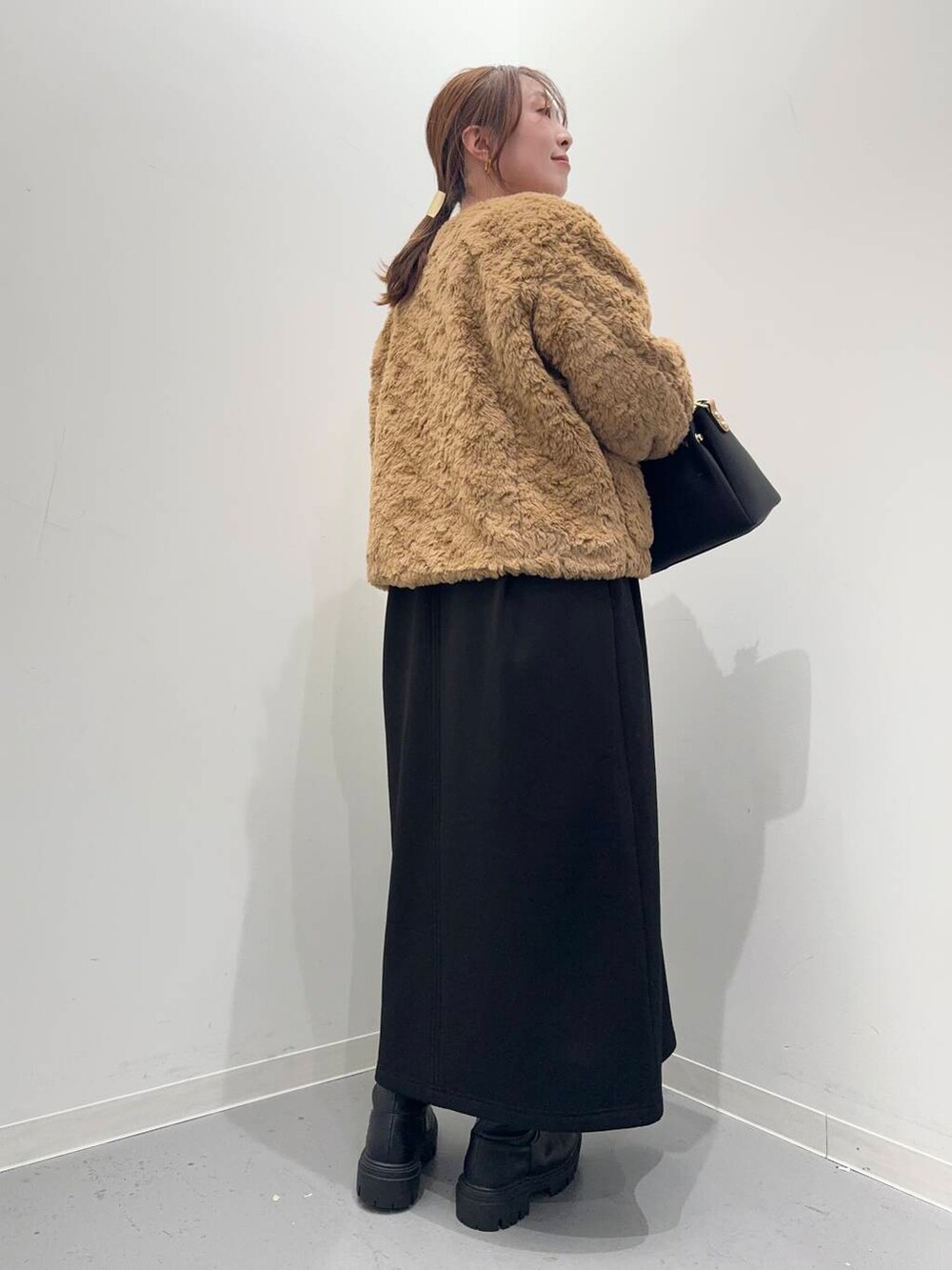 ブラック系のトートバッグ、ブラック系のブーツ、イエロー系のその他アウターを着用したレディースの冬コーディネートの4枚目の写真