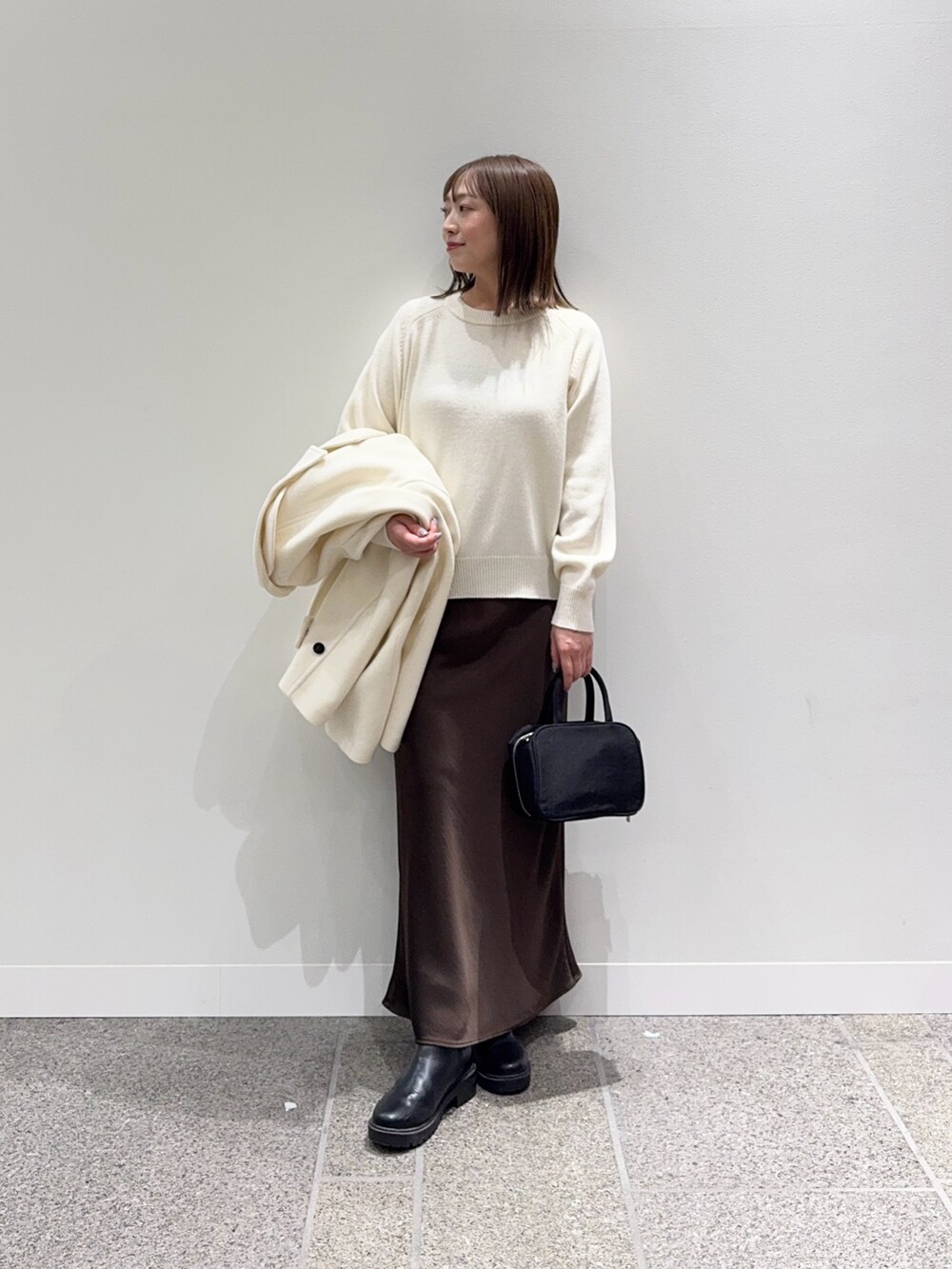 ホワイト系のピーコート、ホワイト系のニット/セーター、ブラック系のボストンバッグを着用したレディースの冬コーディネートの7枚目の写真