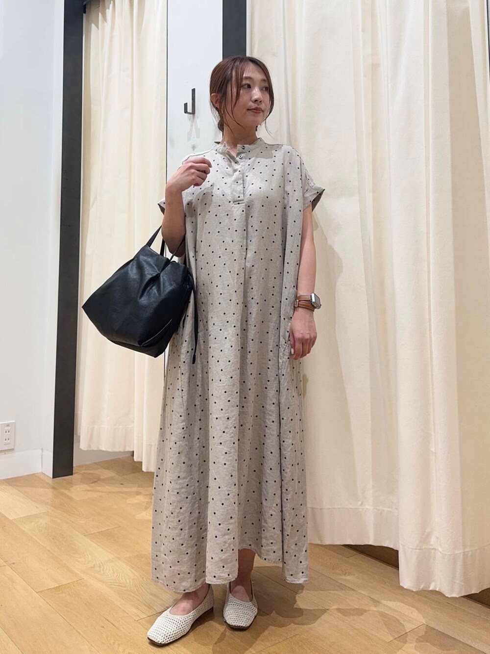 ブラック系のショルダーバッグ、ベージュ系のワンピース、ホワイト系のバレエシューズを着用したレディースの夏コーディネートの5枚目の写真