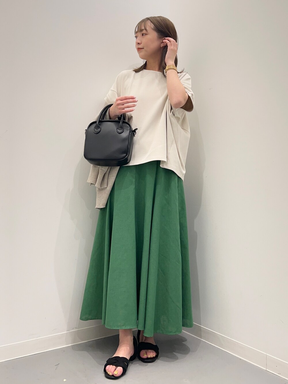 グレー系のTシャツ/カットソー、ブラック系のサンダル、グリーン系のスカートを着用したレディースの春コーディネートの2枚目の写真