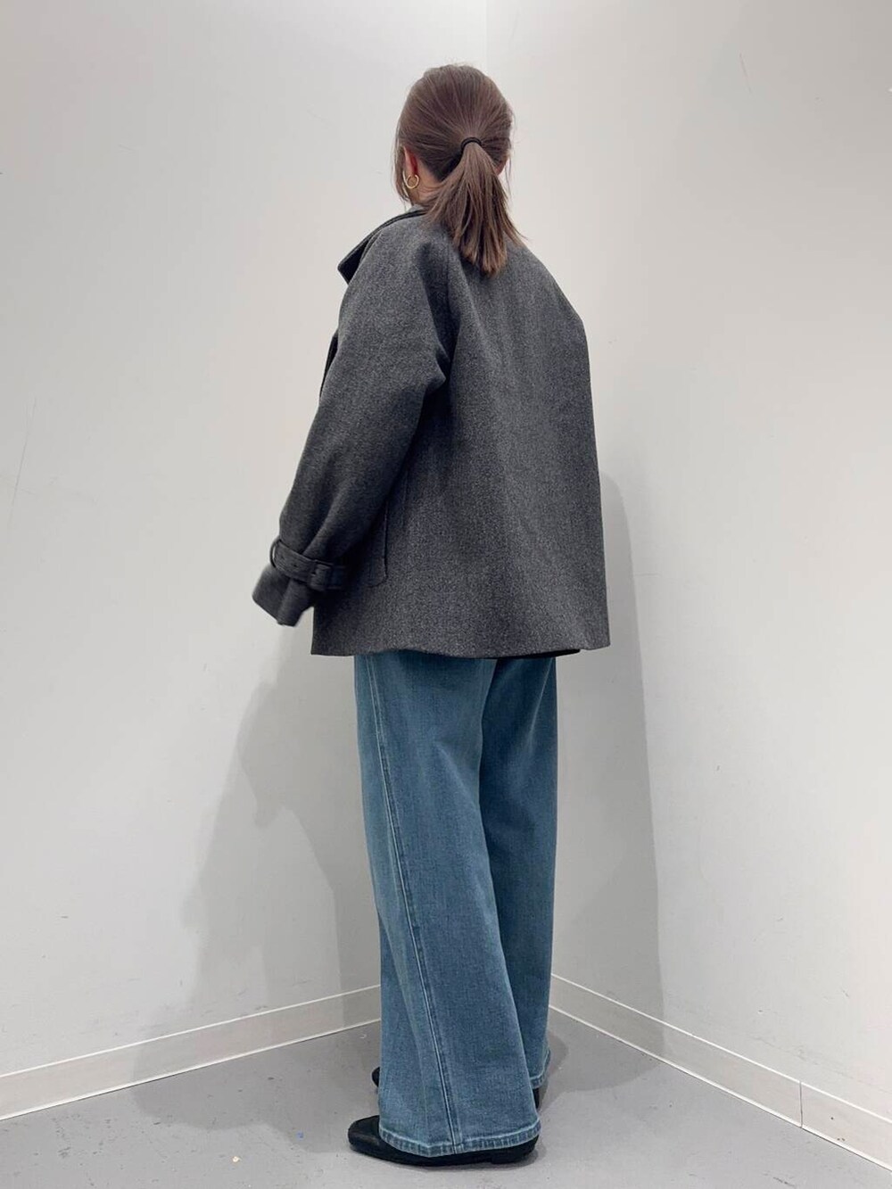 ブラック系のローファー、ホワイト系のショルダーバッグ、グレー系のトレンチコートを着用したレディースの冬コーディネートの2枚目の写真